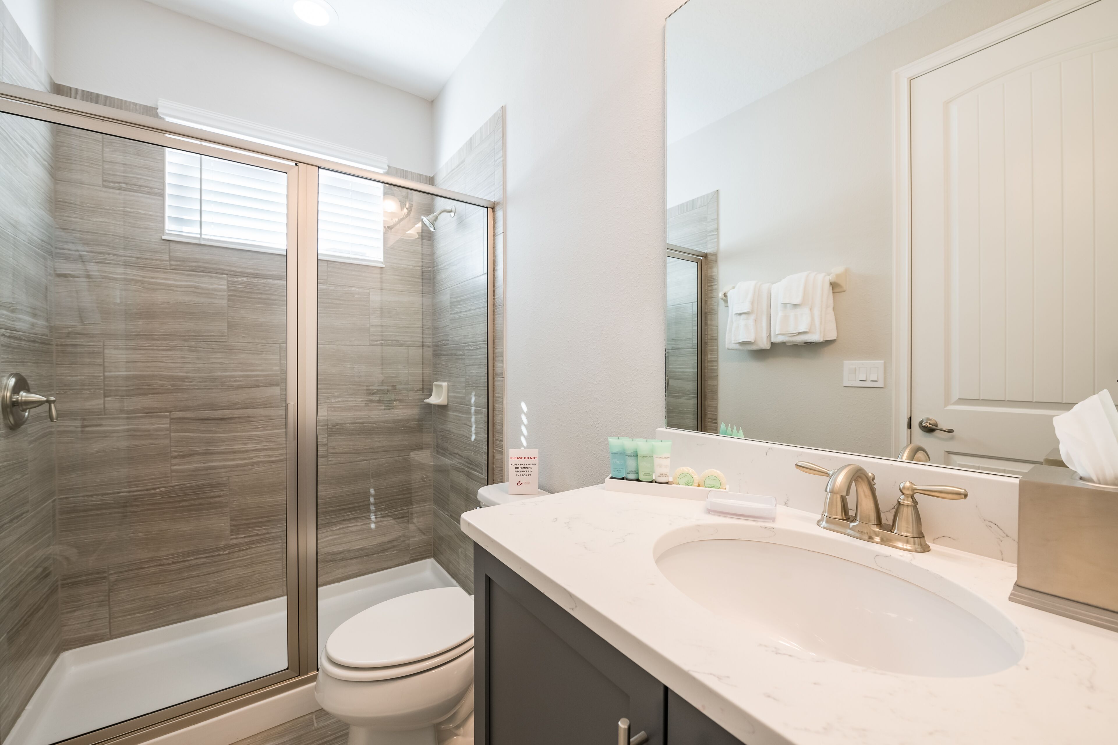 Une salle de bain moderne avec une douche à parois de verre, des toilettes blanches et un lavabo en marbre.