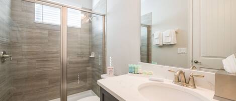Une salle de bain moderne avec une douche à parois de verre, des toilettes blanches et un lavabo en marbre.