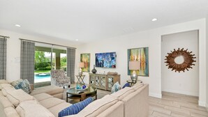 A living room with a sectional sofa, a glass coffee table, a sideboard, and a painting.