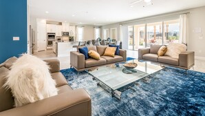 Un salon moderne avec deux canapés, une table basse en verre et un tapis bleu à longues mèches.