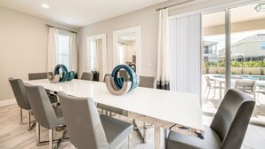 Un espace repas moderne avec une grande table blanche, des chaises grises et des vases décoratifs.
