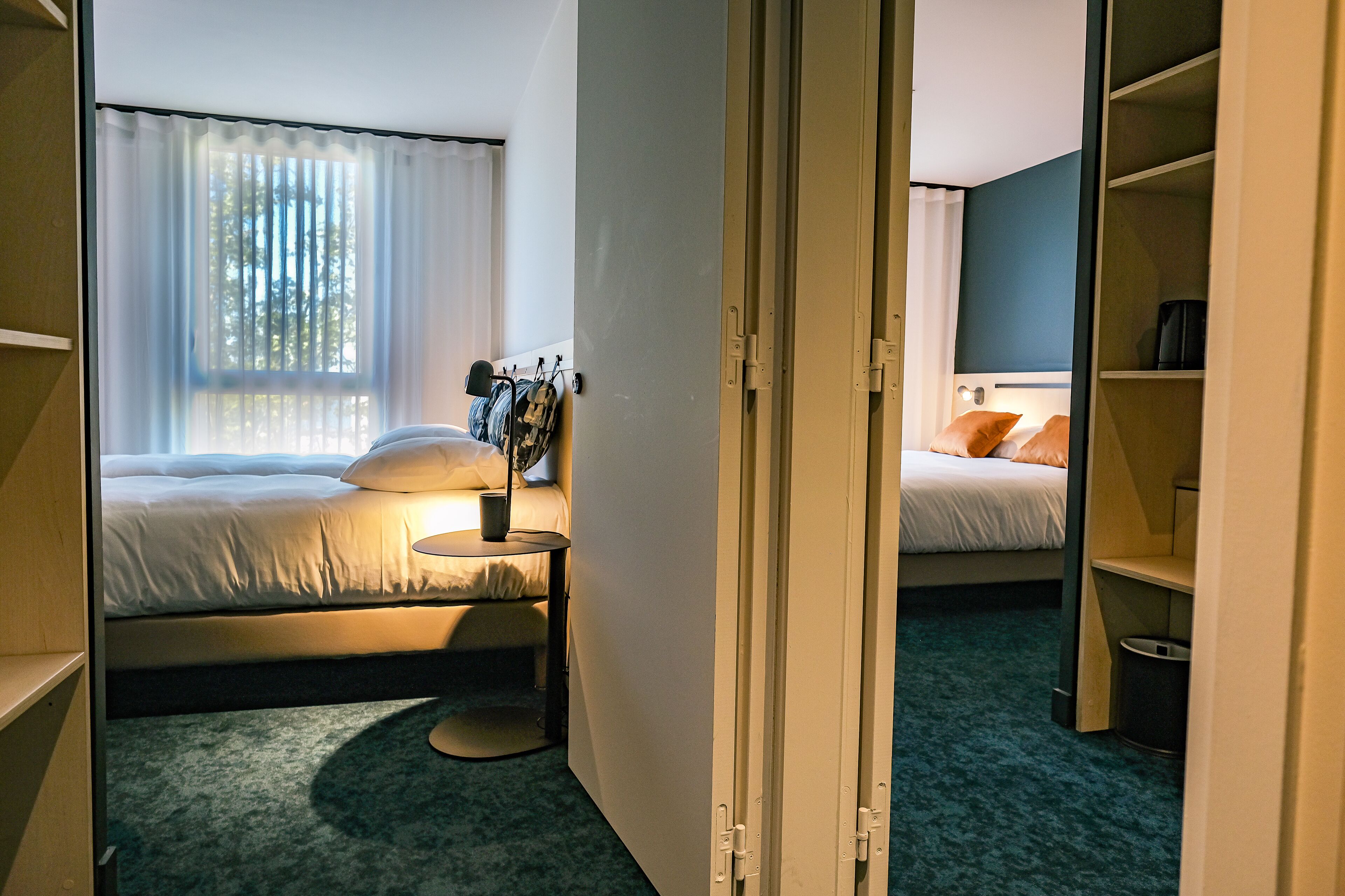 A hotel room with two beds, a small round table, and a closet.