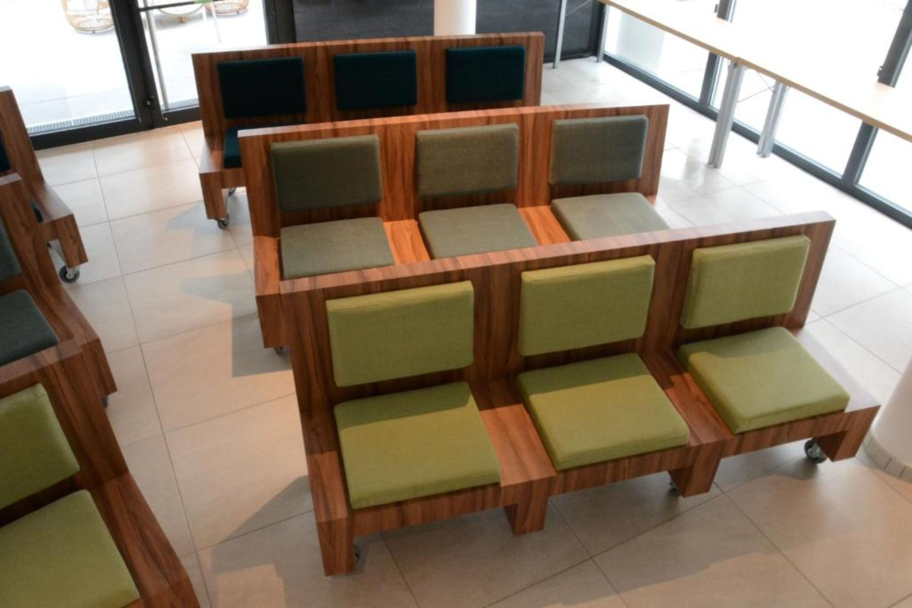 A seating area with wooden furniture and green cushions.
