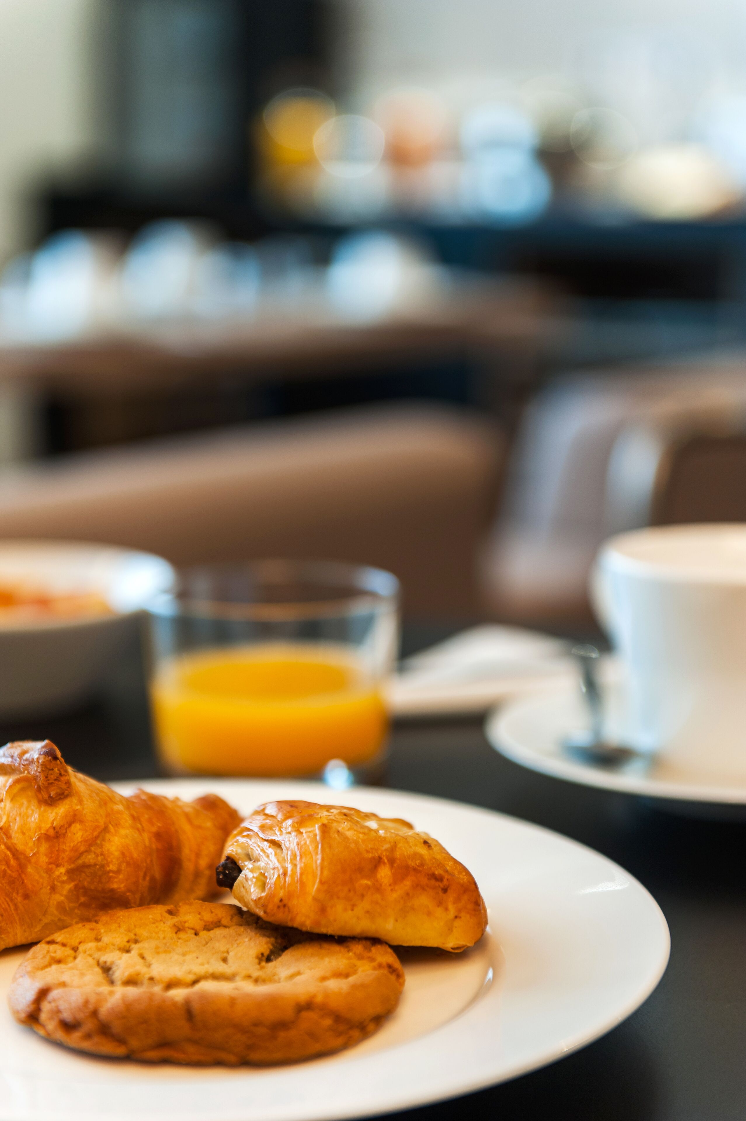 A breakfast setting with croissants and a glass of orange juice on a plate.