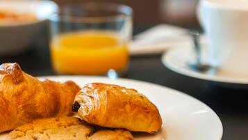 A breakfast setting with croissants and a glass of orange juice on a plate.