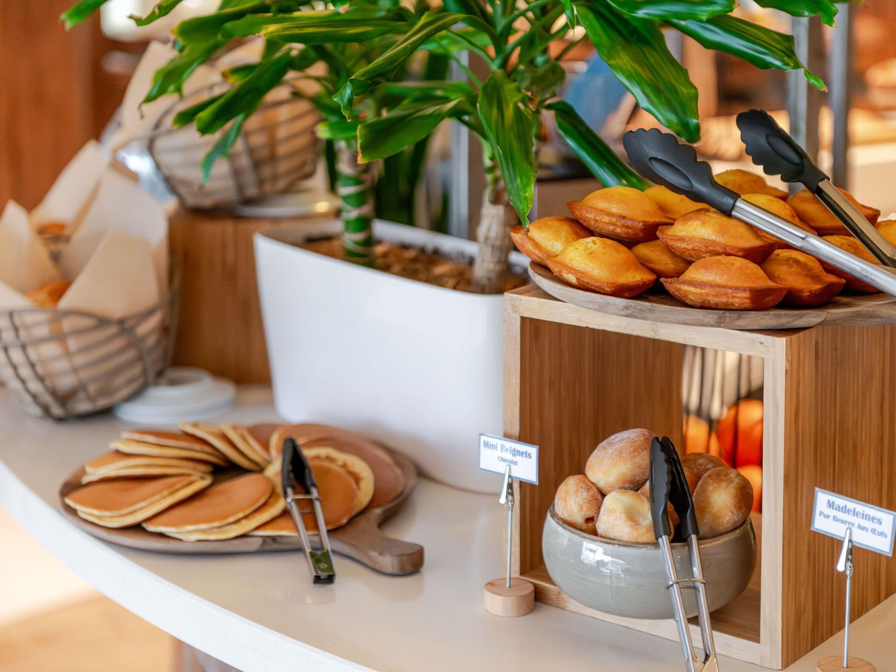 Un buffet con mini beignet, pancake e una ciotola di panini.