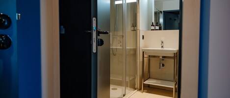 Un bagno moderno con cabina doccia in vetro, lavandino e specchio.