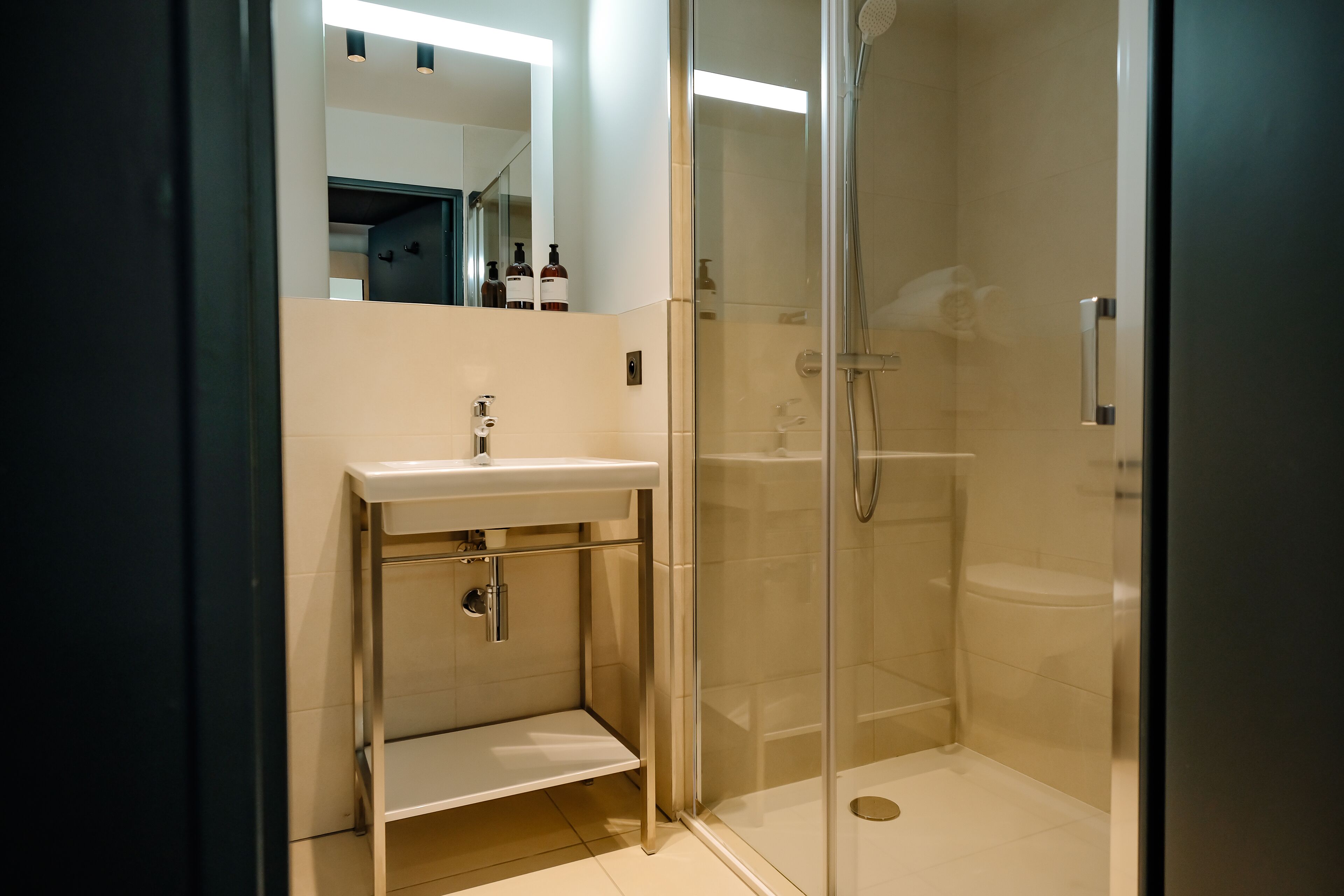 A modern bathroom with a glass-enclosed shower, a white sink, and a mirror above it.