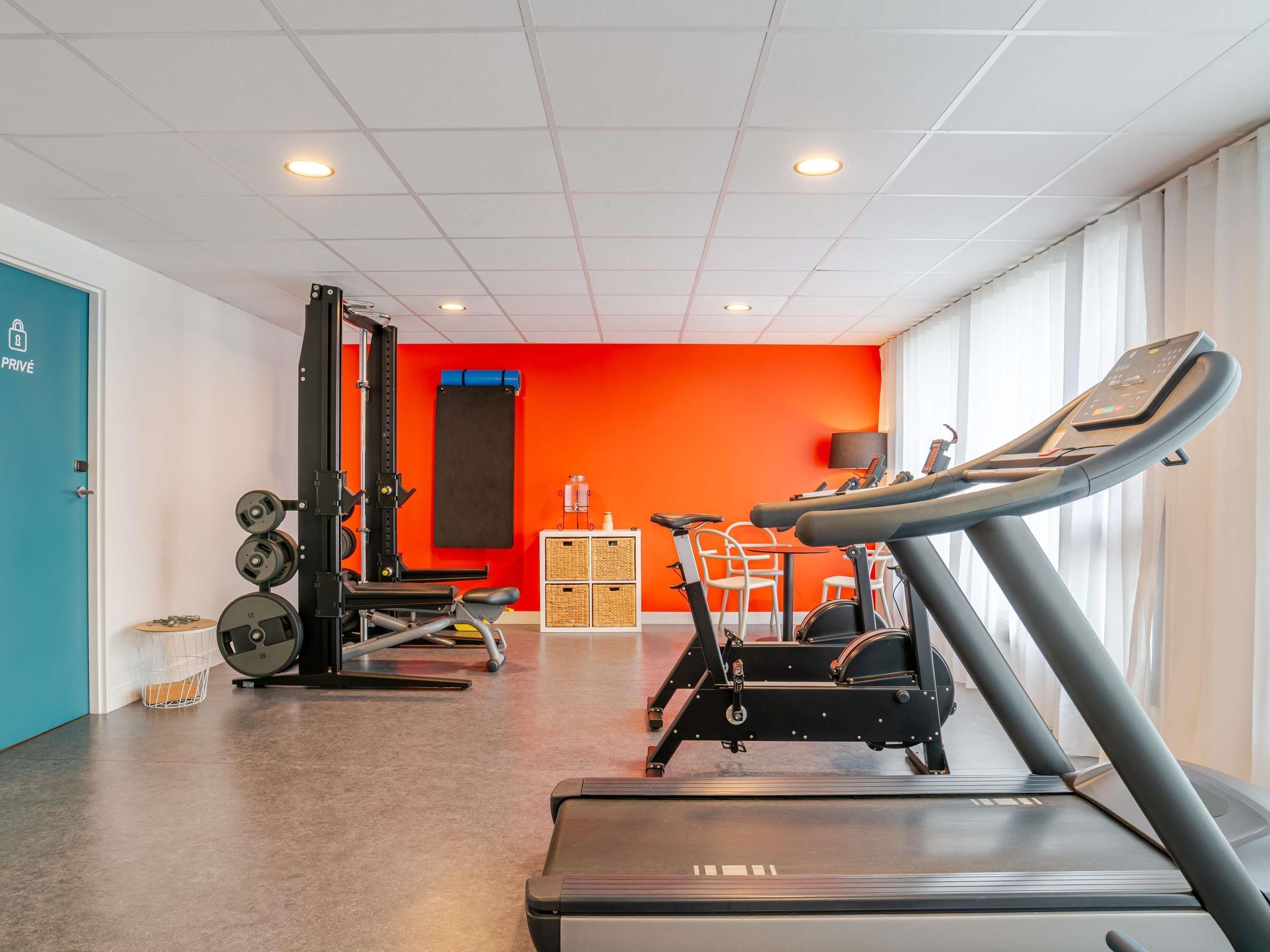 A gym with a treadmill, weight bench, and weights.