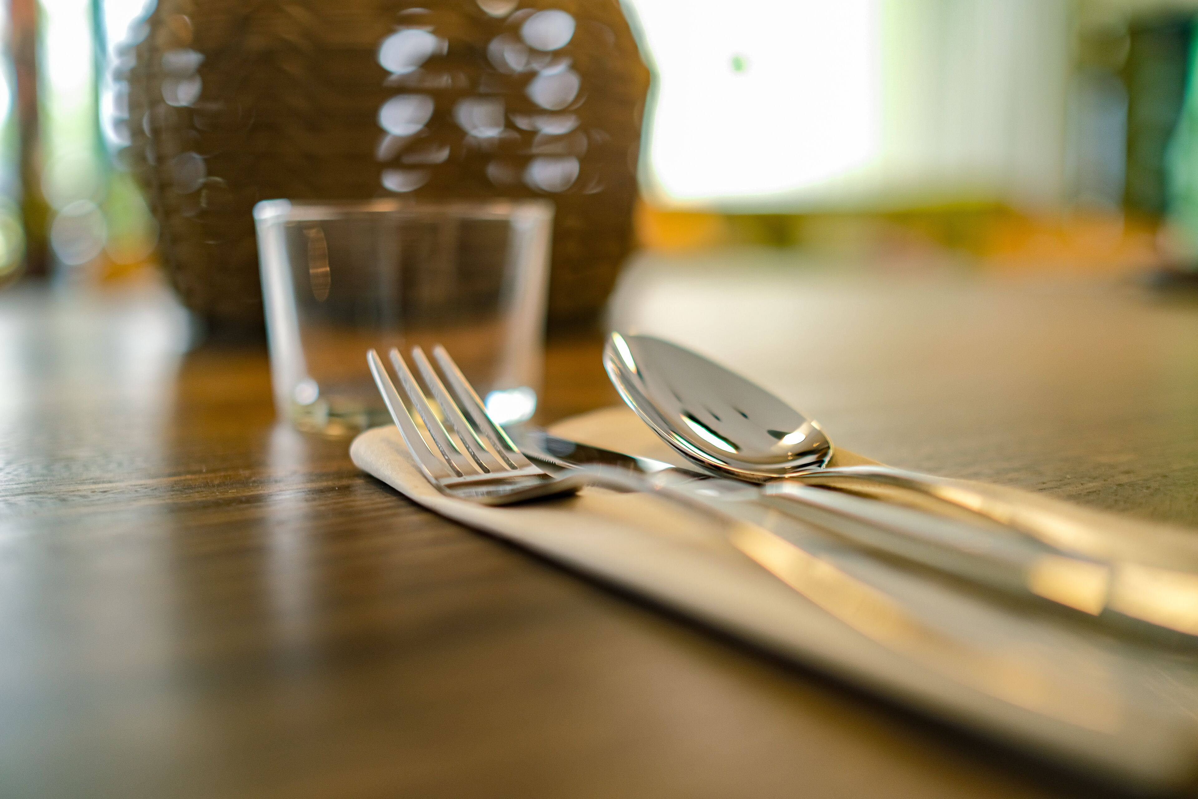 A dining table with a clear glass, a fork, and a spoon.