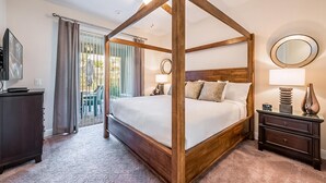 A four-poster bed with a wooden frame, a nightstand with a lamp, and a television on a dresser.