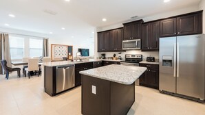 Una cocina moderna con armarios oscuros, electrodomésticos de acero inoxidable y una isla central.