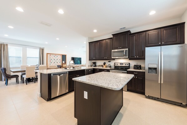 A modern kitchen with dark cabinets, stainless steel appliances, and a central island.
