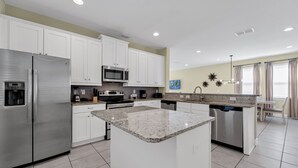 A modern kitchen with white cabinets, stainless steel appliances, granite countertops, and a central island.