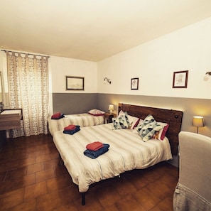 Een slaapkamer met twee bedden, een houten hoofdbord, een klein nachtkastje met een lamp en een stoel.