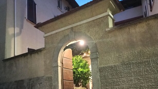 Una entrada d'arc de pedra a un edifici, amb un camí de maons que hi mena.