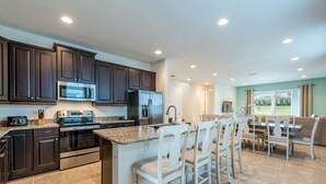 A modern kitchen with dark cabinets, stainless steel appliances, and a central island with bar stools.