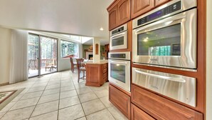 Una cocina con hornos empotrados y un comedor con vistas al exterior.