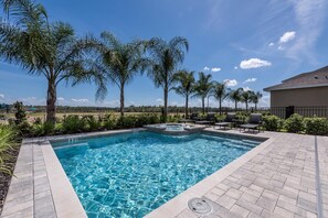 A rectangular swimming pool with a hot tub, surrounded by a brick patio, palm trees, and outdoor furniture. - Modern Home near Disney: Private Pool, Media Room & Waterpark - 7576MR (Reunion)