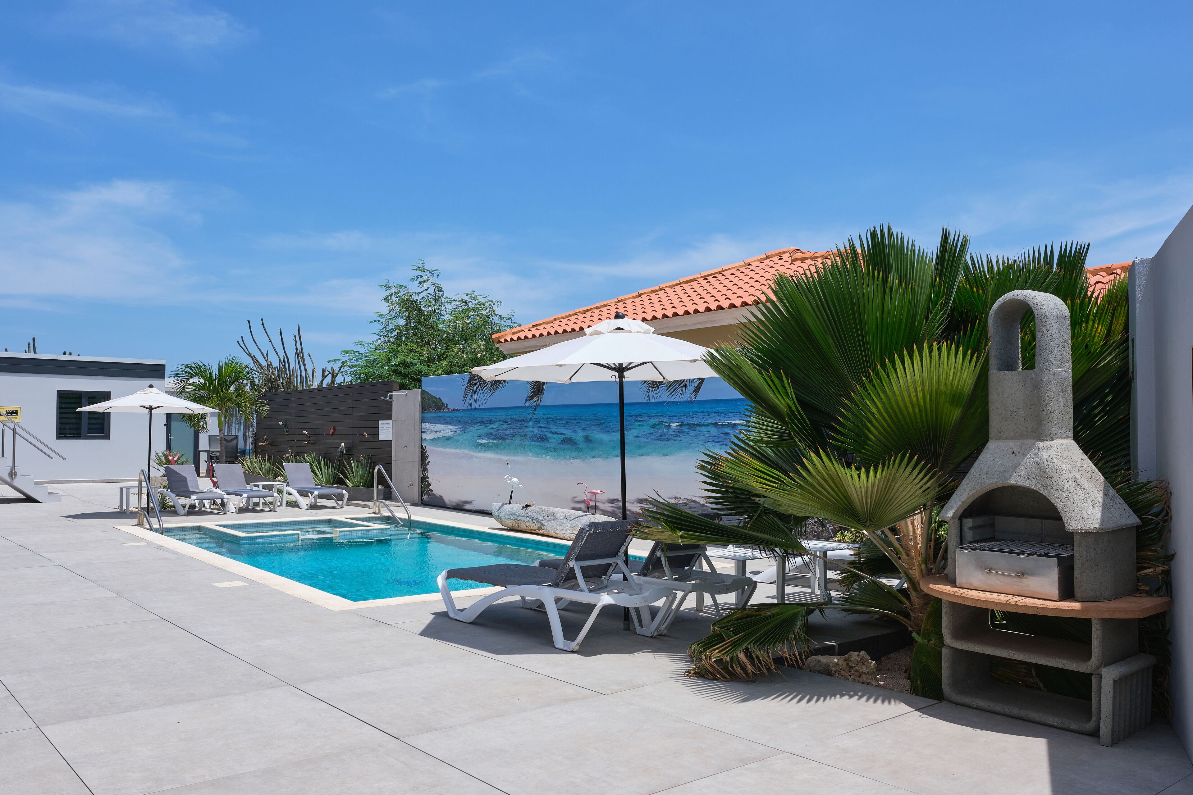 Un área de piscina con sillones de descanso y una parrilla de piedra.
