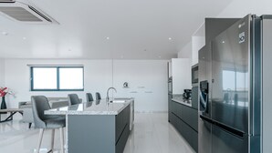 A modern kitchen with a central island, stainless steel appliances, and a large window providing natural light. - Gray Door Apartments - Adults Only (Noord)