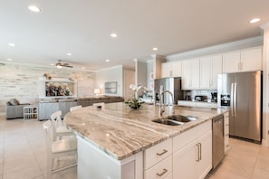 A modern kitchen with white cabinetry, a marble countertop, stainless steel appliances, and a built-in island with seating.