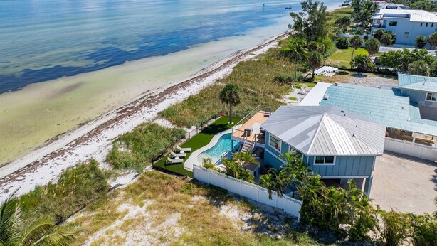 A beachfront property with a swimming pool, a covered patio, and a view of the ocean. - Sea La Vie AM: Bay front, pool, hot tub, rooftop deck, and water sports gear! (Anna Maria)