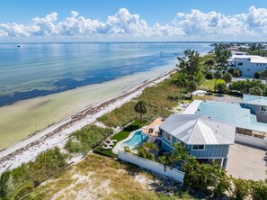 A beachfront property with a swimming pool, a covered patio, and a view of the ocean. - Sea La Vie AM: Bay front, pool, hot tub, rooftop deck, and water sports gear! (Anna Maria)