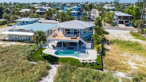 A large, modern house with a swimming pool, multiple decks, and a view of a coastal neighborhood. - Sea La Vie AM: Bay front, pool, hot tub, rooftop deck, and water sports gear! (Anna Maria)