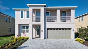 Une maison moderne à deux étages, dotée d’un garage, d’un balcon et d’une pelouse bien entretenue.