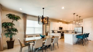 A modern kitchen with white cabinets, a central island, and blue bar stools.