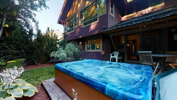 Una casa de dos pisos con jacuzzi en el patio trasero.