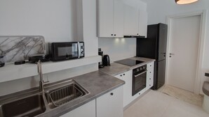 Eine moderne Küche mit weißen Schränken, einem schwarzen Kühlschrank, einer Mikrowelle und einem Spülbecken.