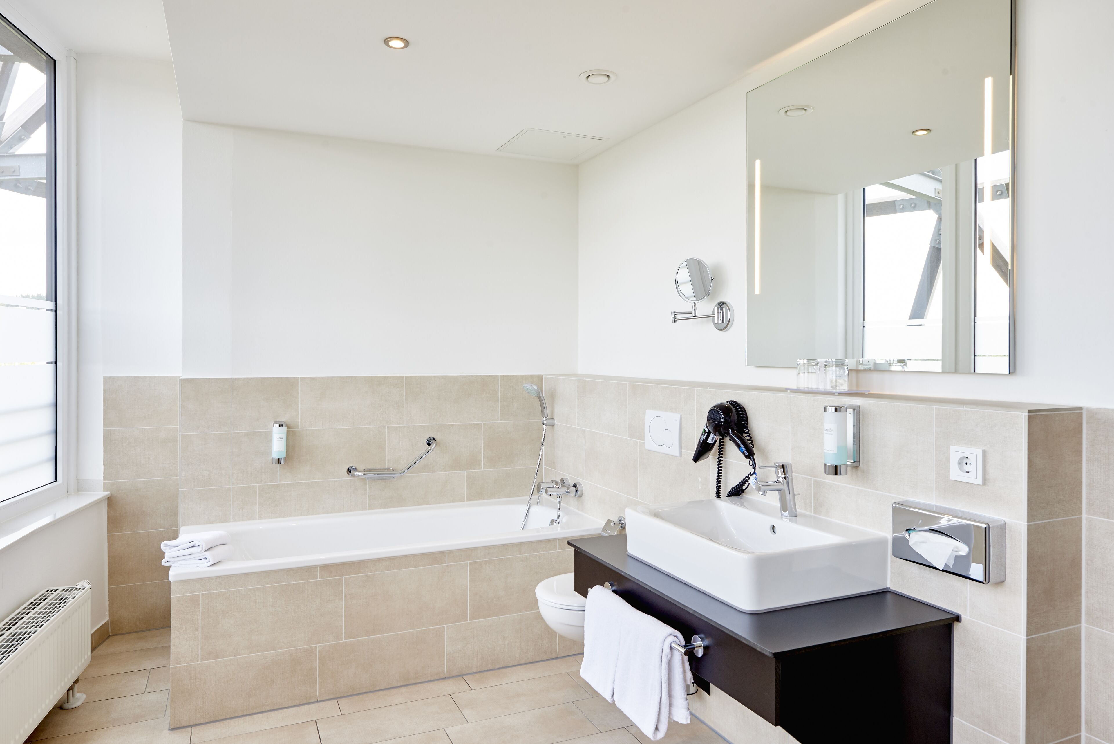 A modern bathroom with a bathtub, a sink, and a large mirror.