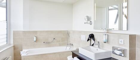 A modern bathroom with a bathtub, a sink, and a large mirror.
