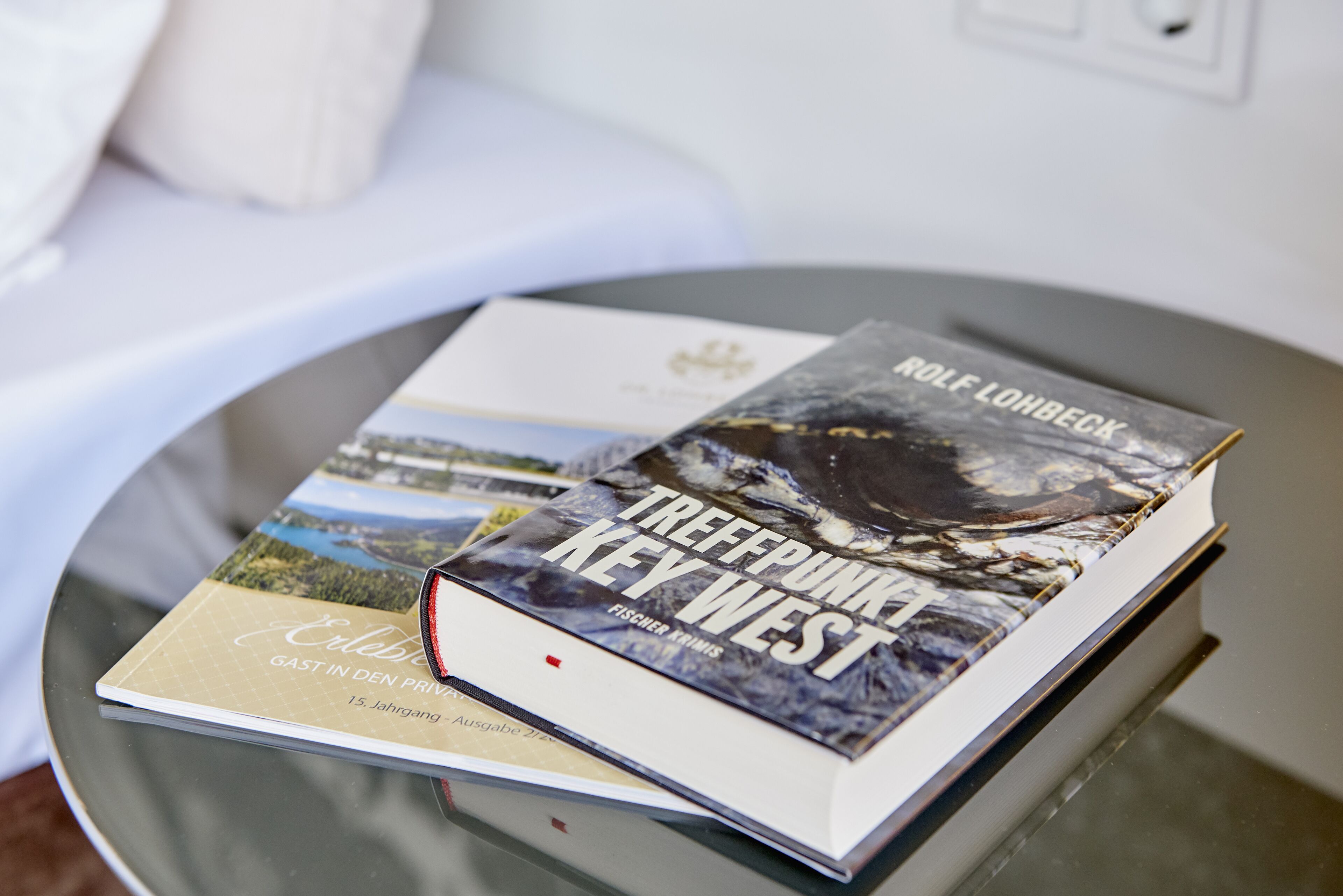 Ein Buch mit dem Titel „TREFFPUNK KEY WEST“ von ROLF LÖHBECK auf einer Glastisch.
