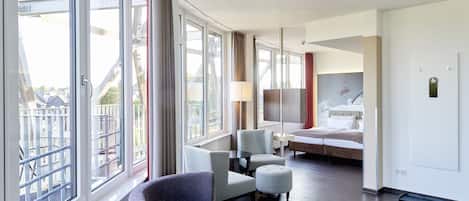 A hotel room with a large window, a bed, a desk, and a chair.