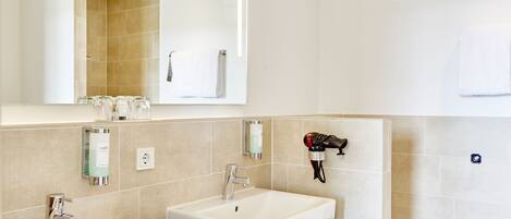 A modern bathroom with two sinks, a large mirror, and a towel rack.