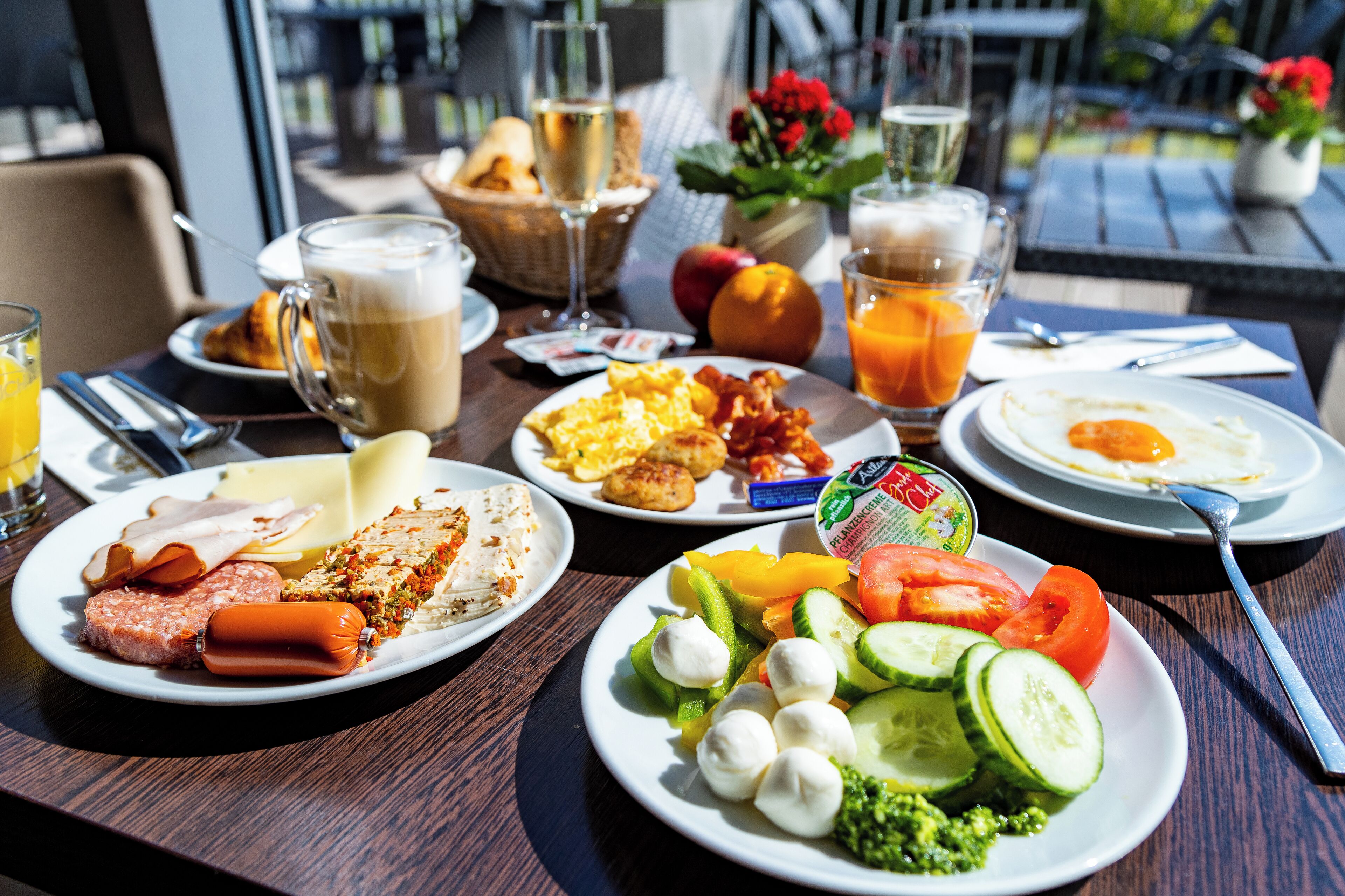 A breakfast table with plates of food, drinks, and a basket of bread.