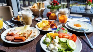A breakfast table with plates of food, drinks, and a basket of bread.