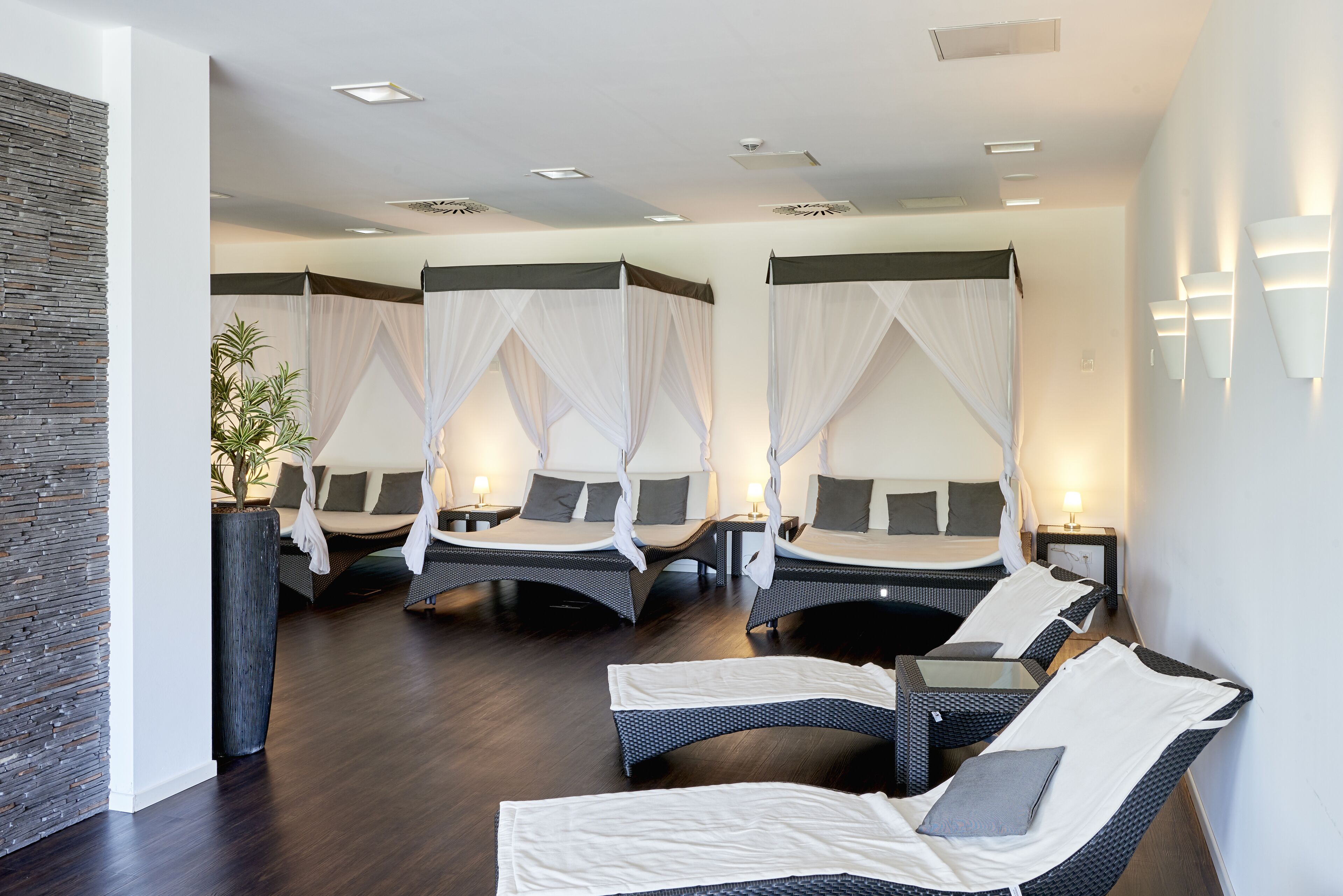 A spa suite with three beds, each with a canopy, and two lounge chairs.