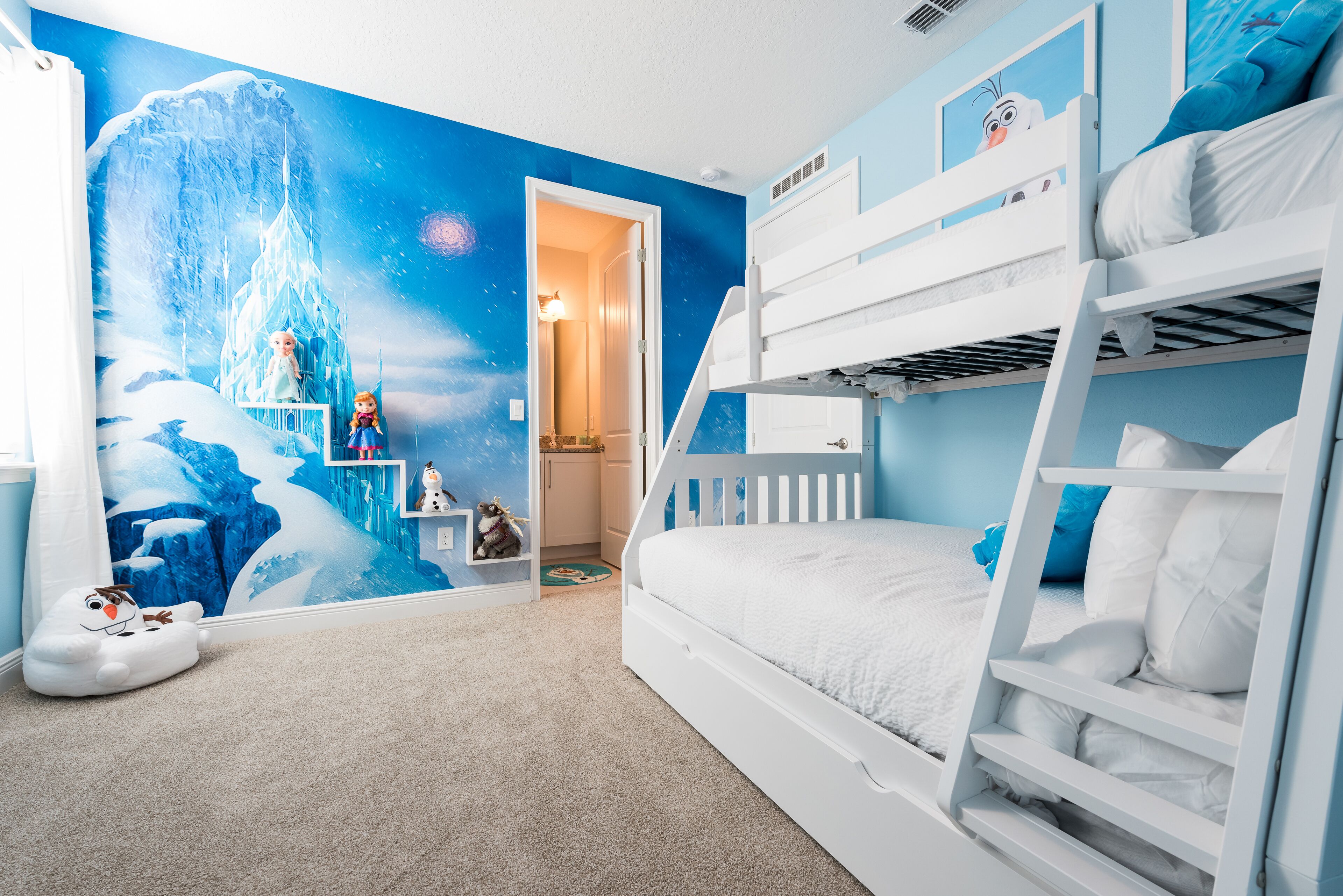Een kinderkamer met stapelbedden, een muurschildering van een besneeerd landschap en een klein rekje met speelgoed.