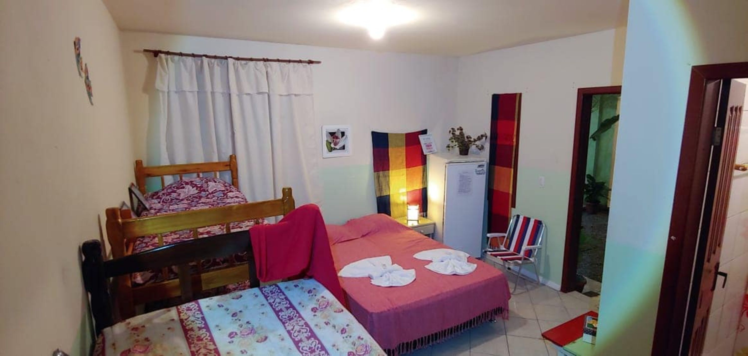 Un dormitorio con cama, una silla, una mesita y una ventana con cortinas.
