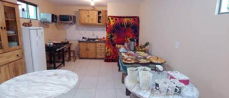 Cocina compacta con armarios de madera, un refrigerador, un microondas y una mesa de comedor con sillas.