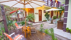 Un patio con mobiliario de madera, sombrillas y plantas en macetas.