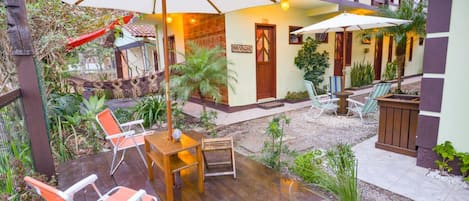 Un patio con mobiliario de madera, sombrillas y plantas en macetas.