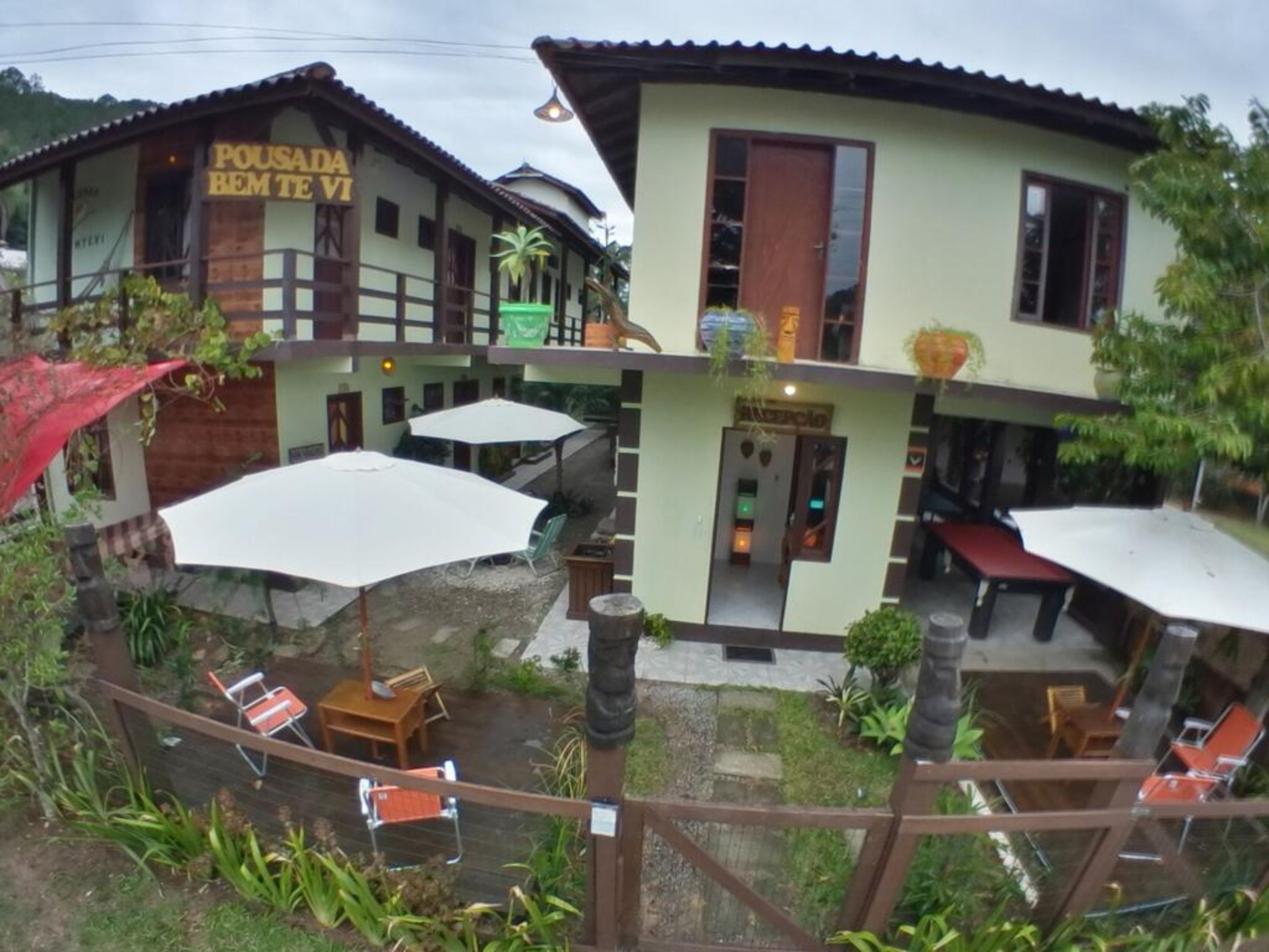 Il s’agit d’un bâtiment à deux étages, sur lequel on peut lire l’inscription « Pousada Bem Te Vi ». Il y a des espaces extérieurs aménagés avec des parasols et des chaises.