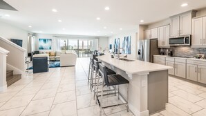 A modern kitchen with a central island, stainless steel appliances, and a dining area with bar stools.