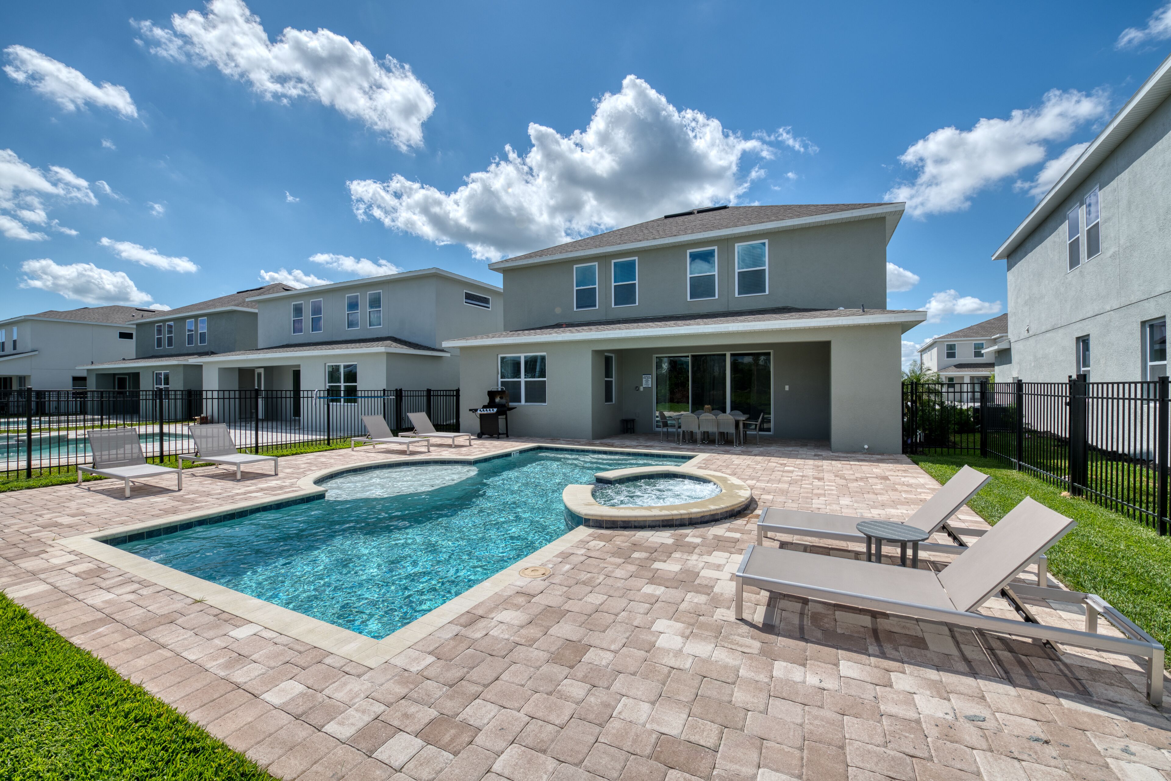 A residential complex with a swimming pool, outdoor seating, and a covered patio area.