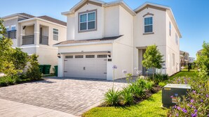 A two-story residential building with a garage, a driveway, and a well-maintained garden with flowering plants.